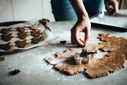 Kitchen counter with cookie dough and a person cutting out figures