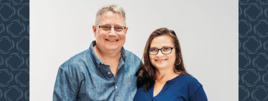 a man and woman smiling and standing together