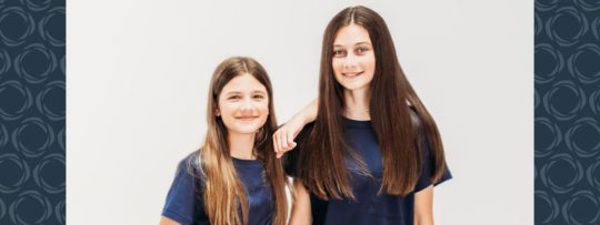 Two young girls stand together and pose for a photo