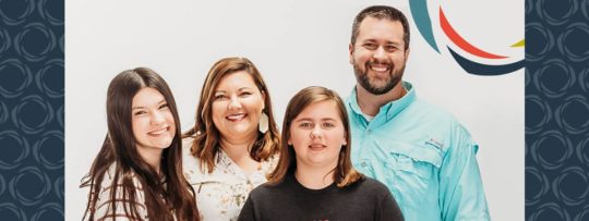 A family of four smile and pose for a photo
