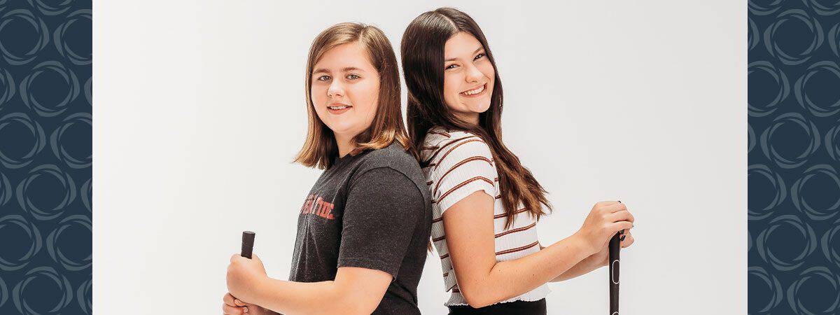 Two young girls pose with their backs to each other
