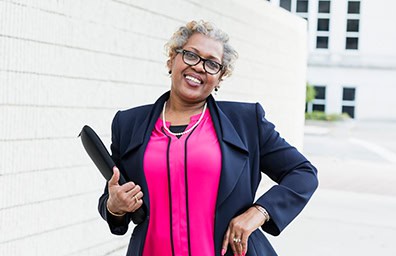 Smiling person dressed in business clothes outside and holding a planner notebook