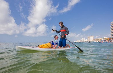 Father and daughter paddleboarding in the Gulf.