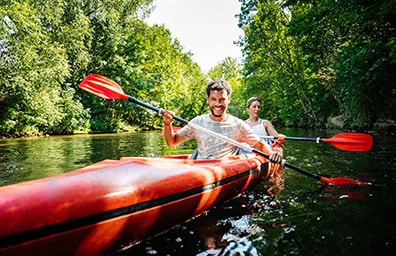 Two people paddling in a kayak along a river