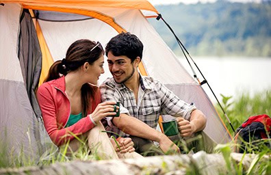 happy young couple camping by lake