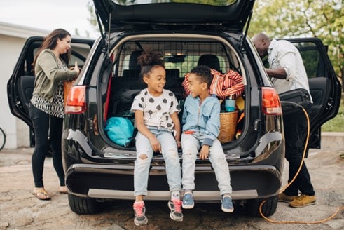Kids sitting in back of open car hatch