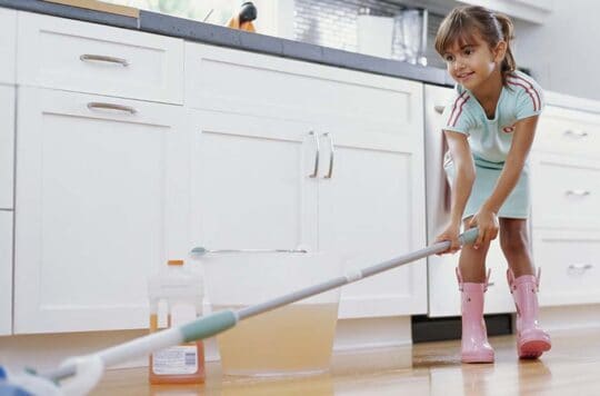 Little girl mopping the floor.