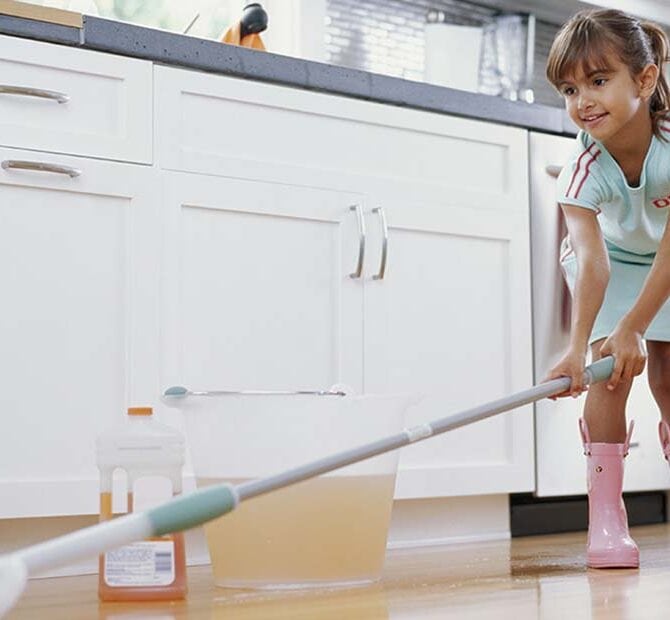 Little girl mopping the floor.
