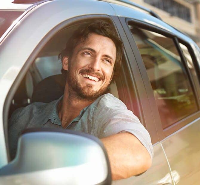 Man staring out car window with smile.
