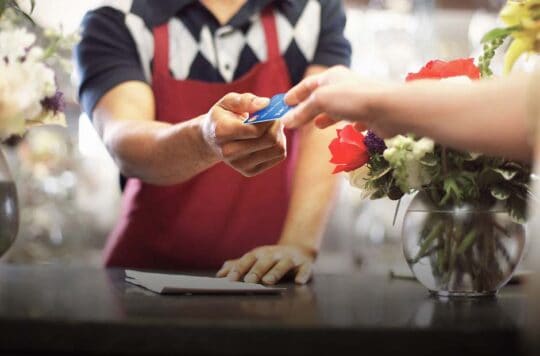man hands credit card back to female customer