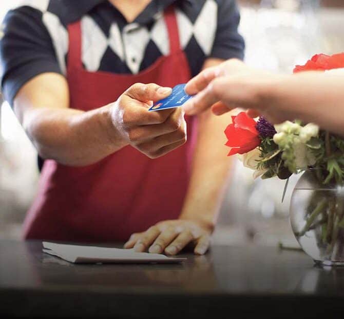 man hands credit card back to female customer