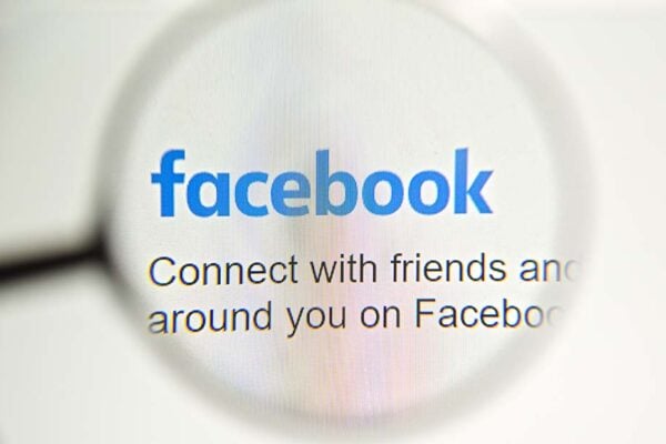 Facebook webpage with a magnifying glass focused on the Facebook logo.