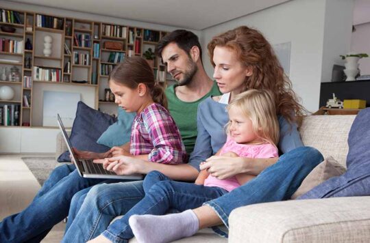 Family of four on couch with laptop
