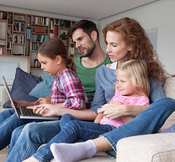 Family of four on couch with laptop