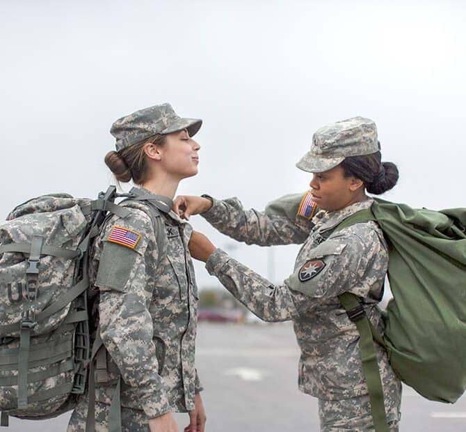 Female Soldier Helping Another Soldier with Shirt