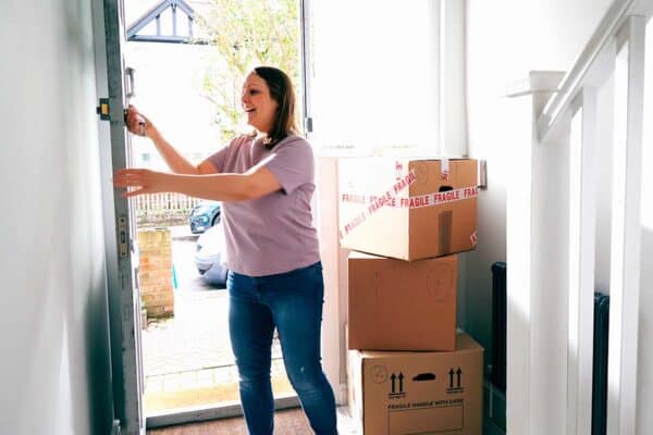 woman unlocks door next to moving boxes