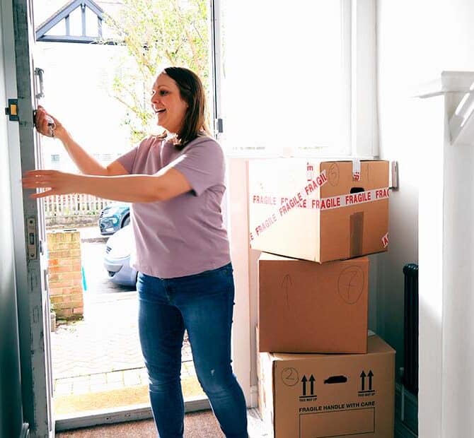 woman unlocks door next to moving boxes