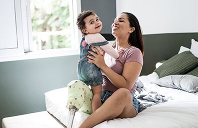 Parent and child smiling sitting on a bed