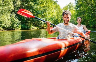 Two people paddling in a kayak along a river