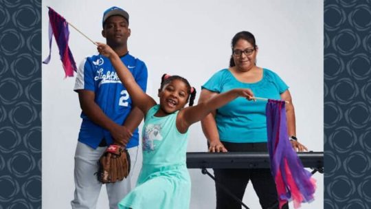 A family of three with a little girl holding streamers