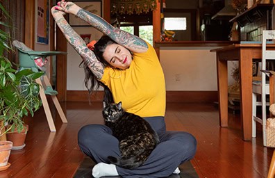 Person doing yoga with a cat on their lap