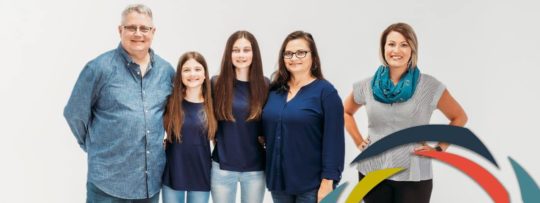a family of four stand together with their financial advisor