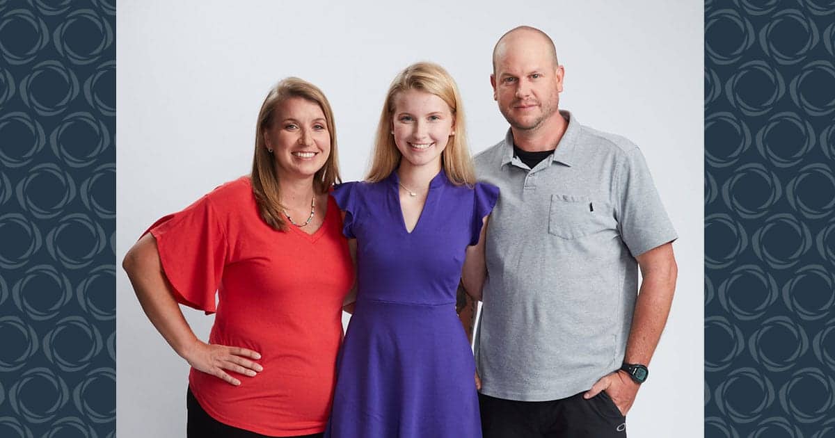 A family of three pose for a photo.