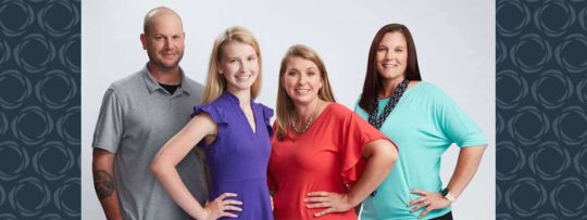A family of three pose for a photo with their financial advisor