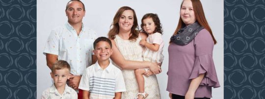 A family of five pose for a photo with their financial advisor.