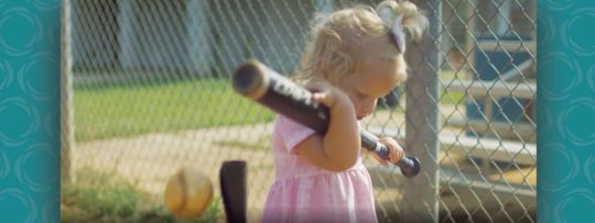a young girl holding a baseball bat