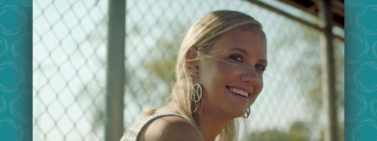 a woman looks off into the distance behind a fence