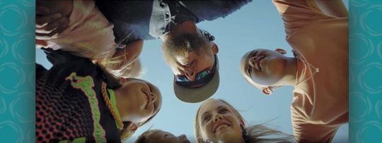 a family huddles together with smiling faces