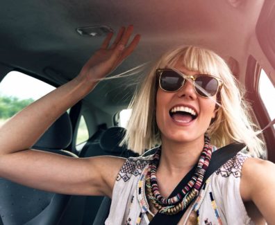 Young happy person smiling in their car